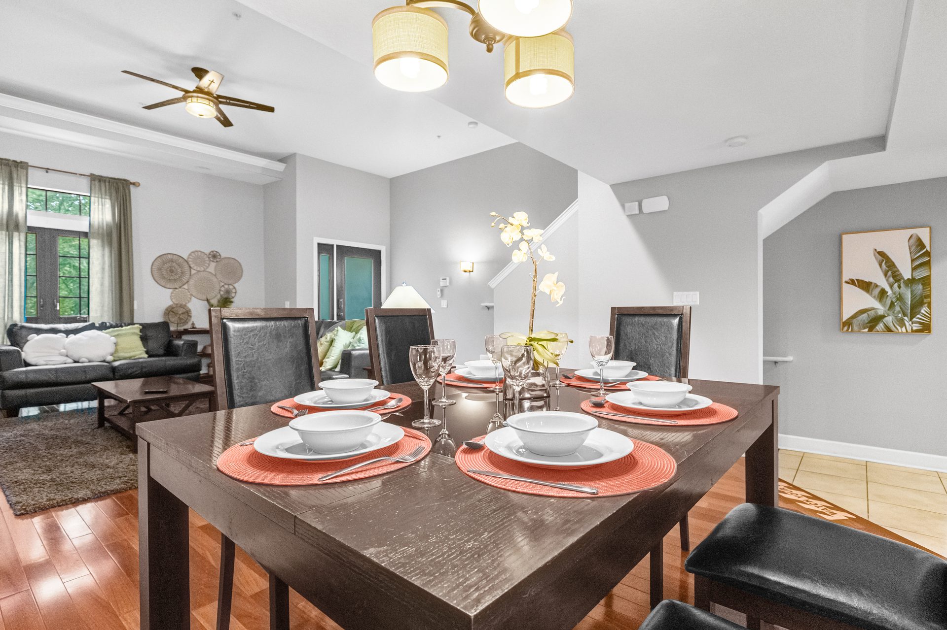 Dining table with orchid centerpiece beneath pendant chandelier
