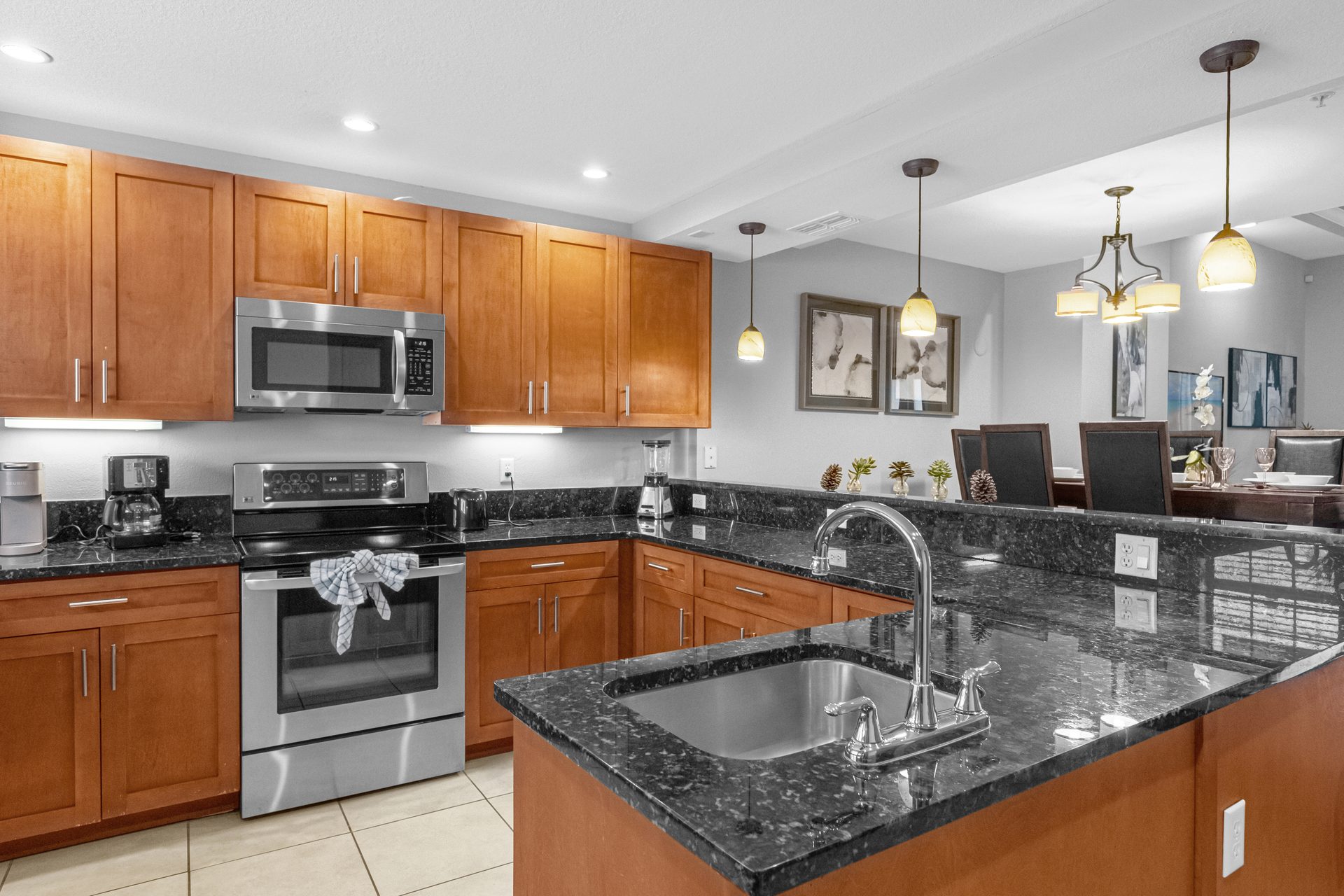 Granite island kitchen with stainless appliances and pendants