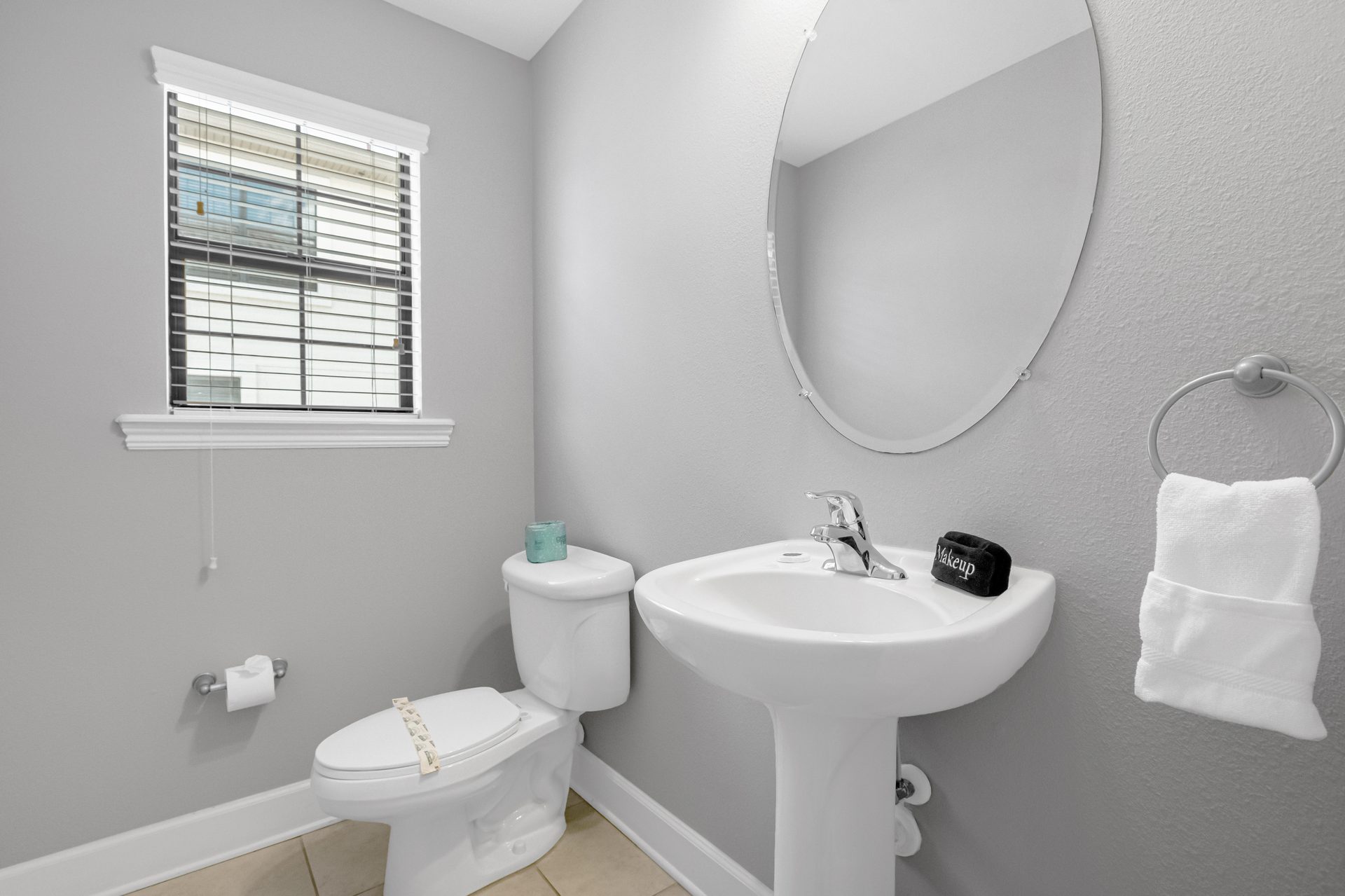 Powder room with pedestal sink and oval mirror